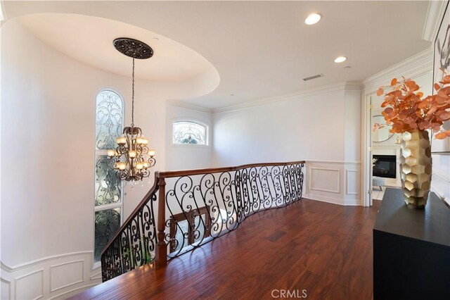 hallway featuring dark hardwood / wood-style floors, ornamental molding, and an inviting chandelier