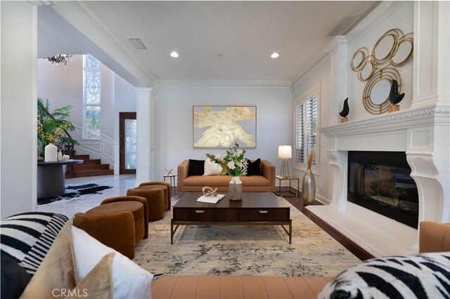 living room with a notable chandelier, ornamental molding, and light hardwood / wood-style flooring