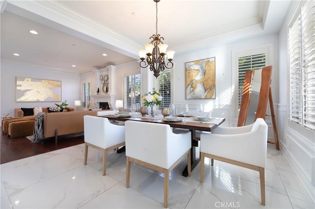 dining space featuring a tray ceiling, an inviting chandelier, and ornamental molding