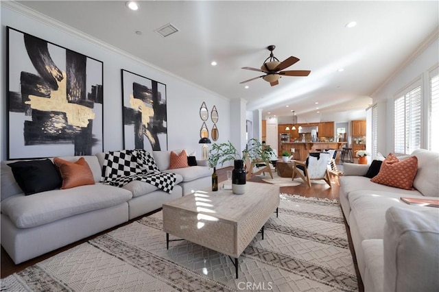 living room with ceiling fan, ornamental molding, and light wood-type flooring