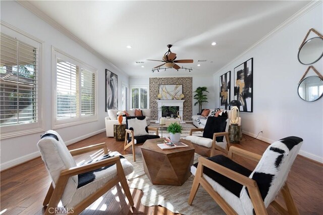 living room featuring ceiling fan, a large fireplace, crown molding, and hardwood / wood-style flooring