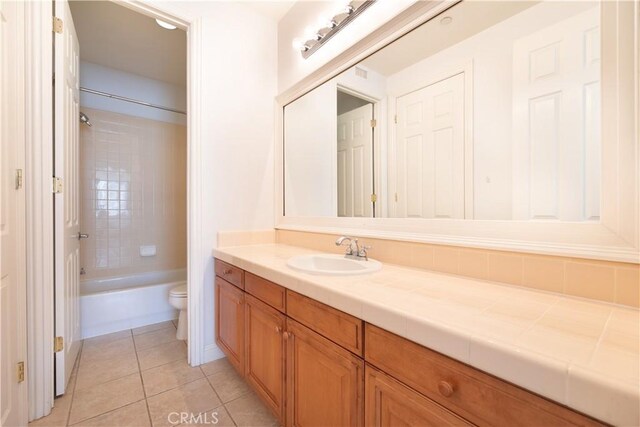 full bathroom with toilet, vanity, tile patterned floors, and tiled shower / bath