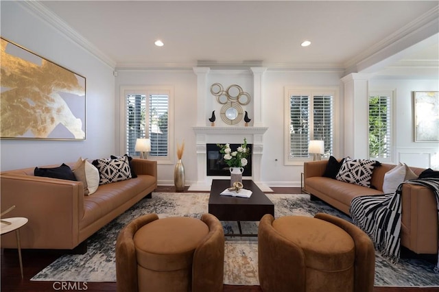 living room featuring hardwood / wood-style flooring, a large fireplace, and crown molding