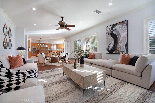 living room featuring ceiling fan, crown molding, and light hardwood / wood-style flooring