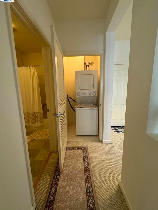 hall with carpet floors and stacked washer / dryer