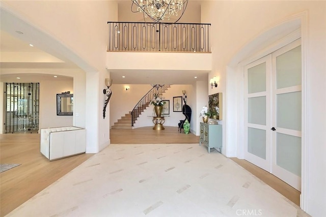 entrance foyer with a towering ceiling, a notable chandelier, and hardwood / wood-style flooring