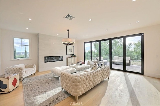 living room with a fireplace, light hardwood / wood-style flooring, and a healthy amount of sunlight