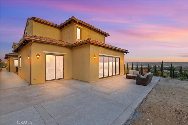 back house at dusk featuring a patio area