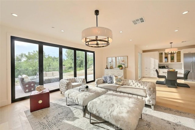 living room with a chandelier, french doors, and light hardwood / wood-style floors