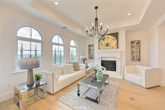 living room with light wood-type flooring and a tray ceiling