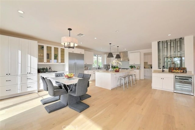 dining room featuring sink, beverage cooler, and light wood-type flooring