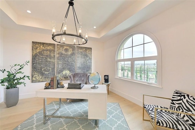 office area with a raised ceiling, light wood-type flooring, and a chandelier