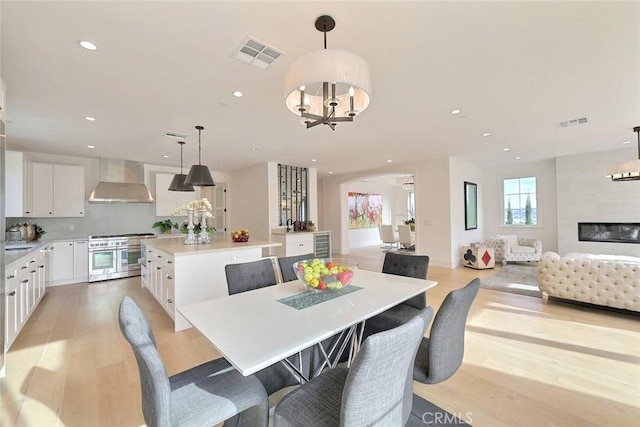 dining room featuring a fireplace, a chandelier, and light wood-type flooring