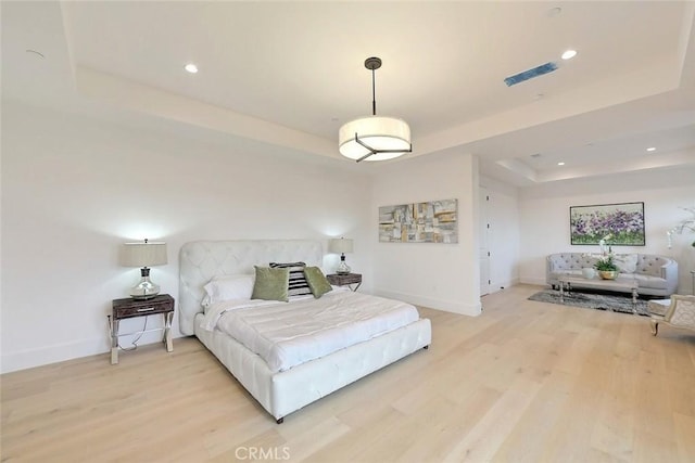 bedroom with wood-type flooring and a tray ceiling