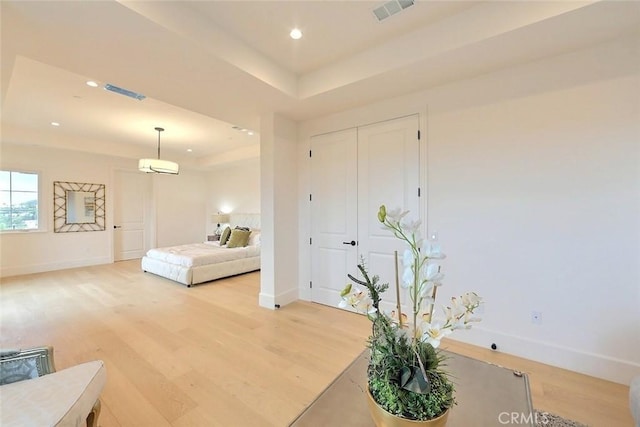 bedroom with wood-type flooring and a raised ceiling