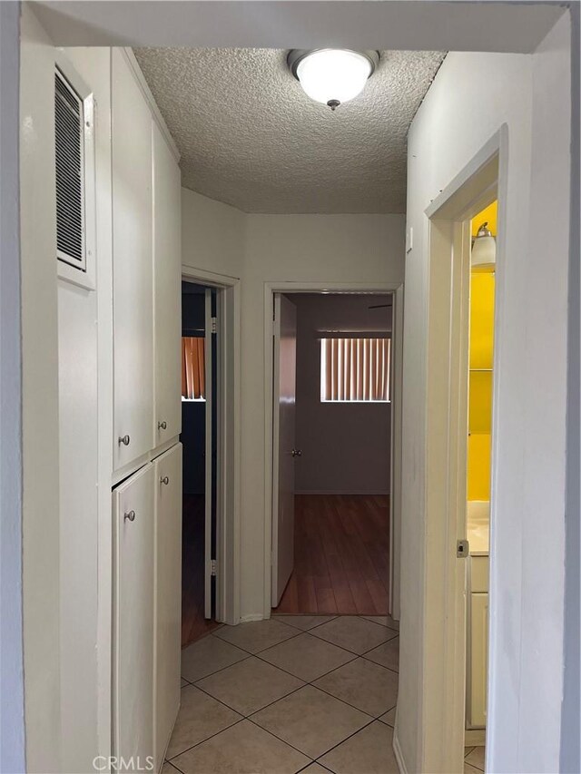 corridor with light tile patterned floors and a textured ceiling