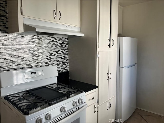 kitchen featuring white refrigerator, light tile patterned flooring, gas range oven, and backsplash