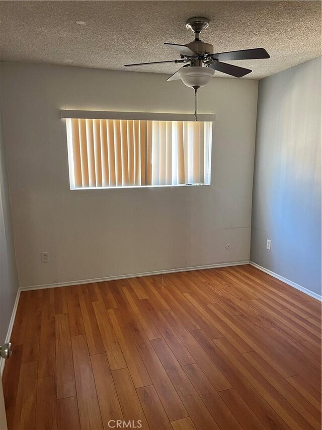 spare room featuring a textured ceiling, hardwood / wood-style flooring, and plenty of natural light