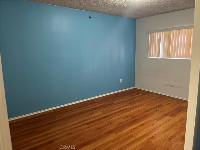 unfurnished room featuring wood-type flooring and a textured ceiling