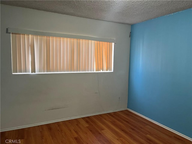 unfurnished room featuring wood-type flooring and a textured ceiling