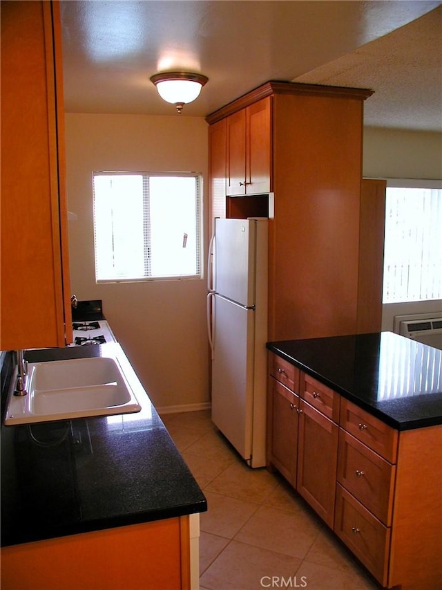 kitchen featuring sink, plenty of natural light, light tile patterned floors, and white refrigerator