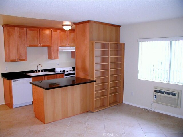 kitchen with a wall mounted air conditioner, light tile patterned floors, white appliances, and sink