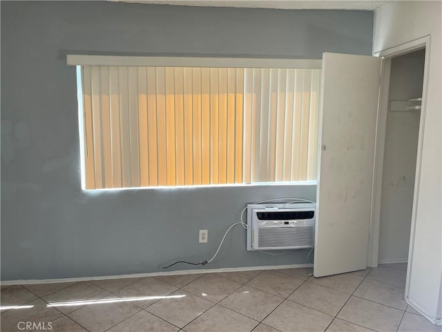 unfurnished bedroom with light tile patterned floors, an AC wall unit, and a closet