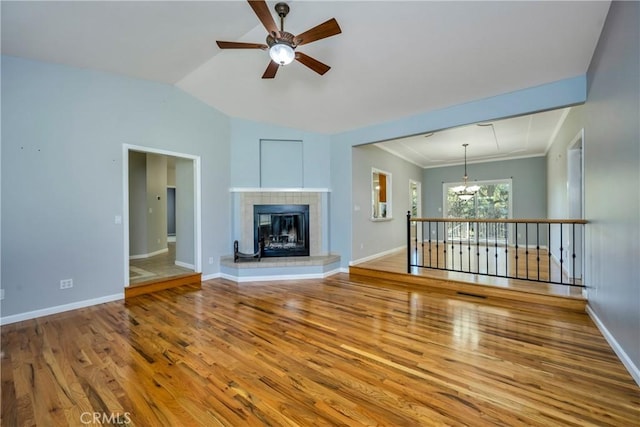 unfurnished living room with a fireplace, vaulted ceiling, ceiling fan with notable chandelier, and hardwood / wood-style floors