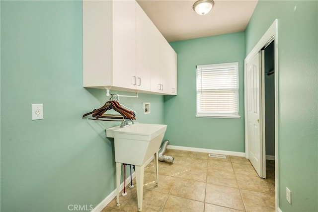 clothes washing area with cabinets, washer hookup, and light tile patterned flooring