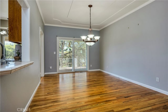 unfurnished dining area with crown molding, wood-type flooring, and a notable chandelier