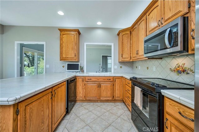 kitchen with black appliances, tasteful backsplash, sink, kitchen peninsula, and light tile patterned floors