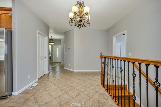 hallway with an inviting chandelier and light tile patterned flooring