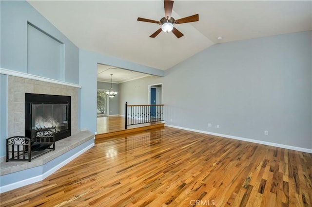 unfurnished living room featuring lofted ceiling, a fireplace, ceiling fan with notable chandelier, and hardwood / wood-style flooring