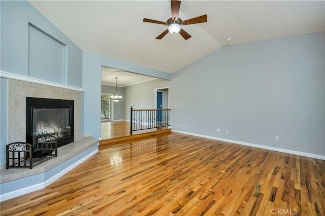 unfurnished living room with a fireplace, ceiling fan with notable chandelier, lofted ceiling, and wood-type flooring