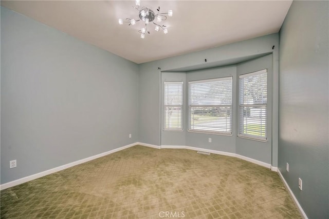 carpeted empty room with an inviting chandelier