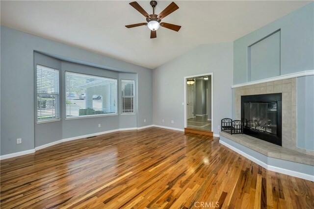 unfurnished living room featuring ceiling fan, vaulted ceiling, a fireplace, and wood-type flooring