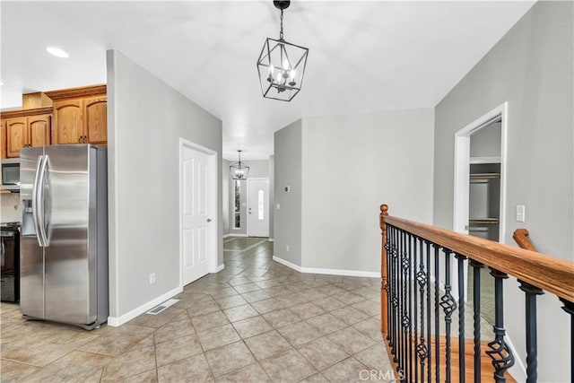 hallway featuring light tile patterned flooring and a notable chandelier