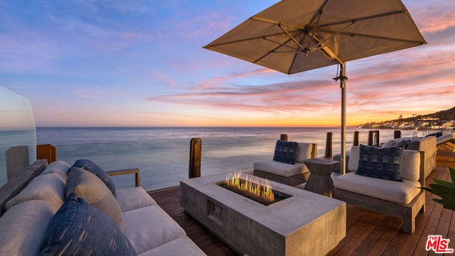 deck at dusk with a water view and an outdoor fire pit