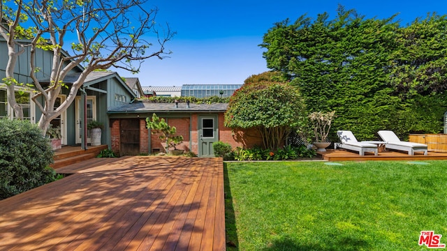 view of front of home featuring a deck, a front lawn, and an outdoor structure