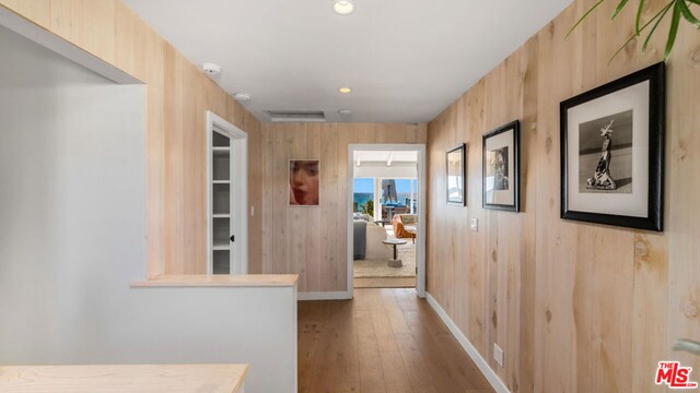 corridor with wooden walls and light wood-type flooring