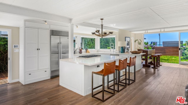 kitchen featuring a center island, dark hardwood / wood-style flooring, white cabinetry, stainless steel appliances, and decorative light fixtures