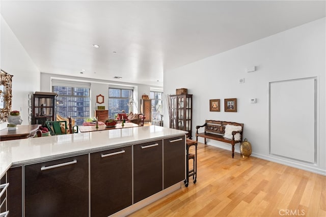 kitchen featuring a kitchen bar, dark brown cabinets, and light wood-type flooring