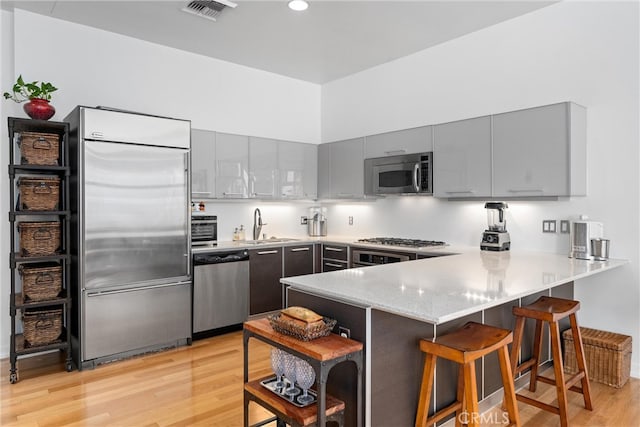 kitchen with light hardwood / wood-style flooring, kitchen peninsula, and stainless steel appliances