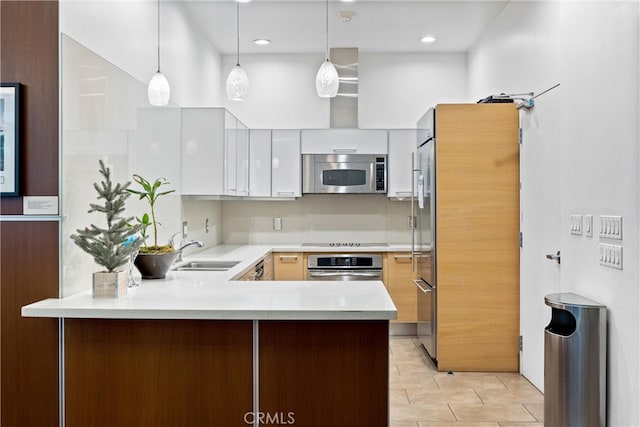 kitchen with sink, appliances with stainless steel finishes, decorative light fixtures, and white cabinets