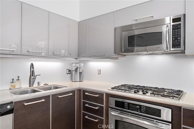 kitchen with stainless steel appliances, dark brown cabinetry, and sink