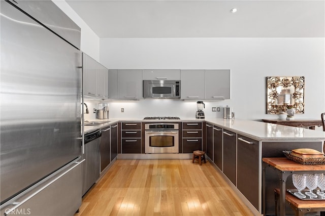 kitchen featuring sink, kitchen peninsula, stainless steel appliances, and light hardwood / wood-style floors