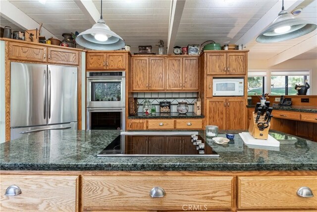 kitchen featuring decorative light fixtures, backsplash, dark stone countertops, and stainless steel appliances