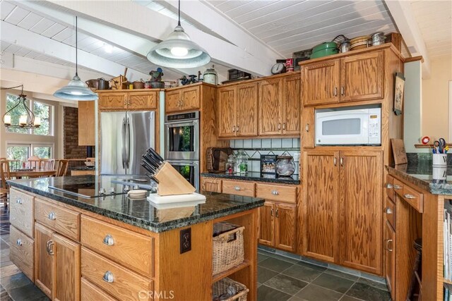 kitchen with a kitchen island, appliances with stainless steel finishes, dark stone counters, and decorative light fixtures