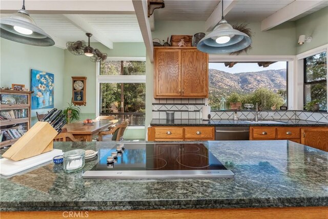 kitchen with decorative light fixtures, stovetop, a mountain view, stainless steel dishwasher, and beam ceiling