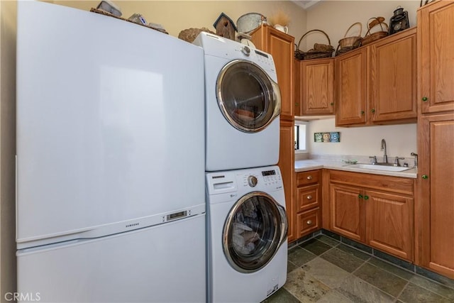 washroom featuring stacked washer / drying machine, sink, and cabinets